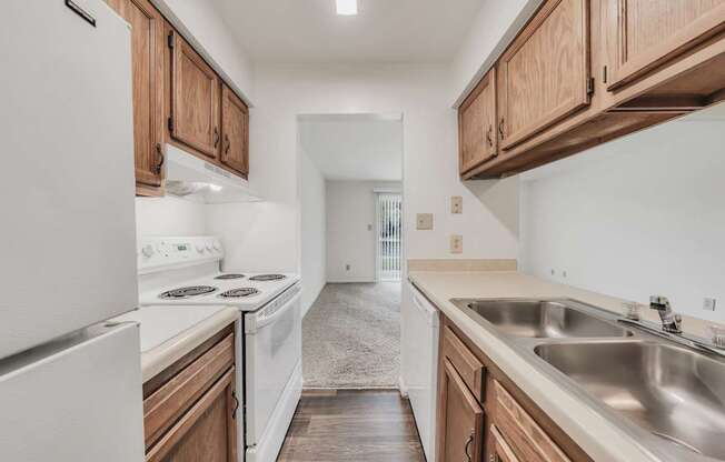 A kitchen with white appliances and wooden cabinets.