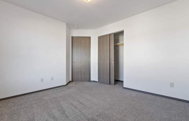 A room with a carpeted floor and two doors.