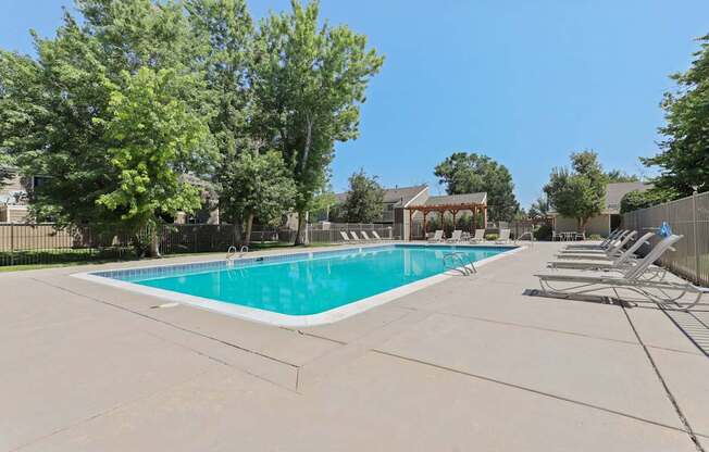 A large swimming pool surrounded by trees and lounge chairs.