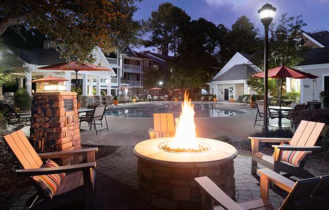 a fire pit in front of a swimming pool at night