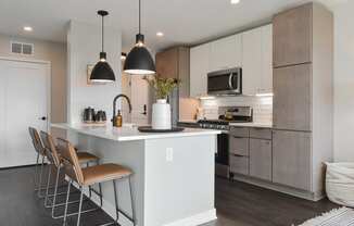 a kitchen with stainless steel appliances and a large island with stools at The Bohen Apartments , Minneapolis, MN, 55408