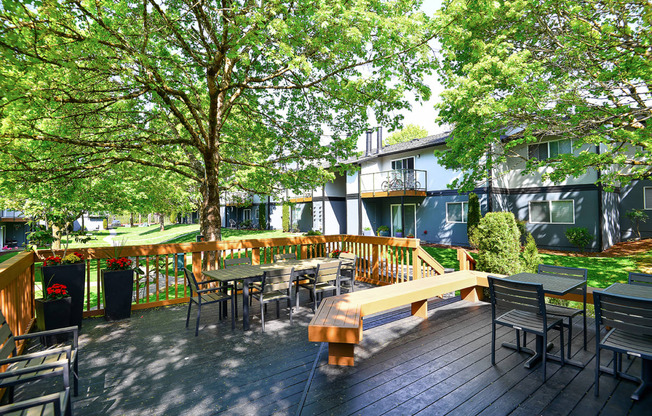 a large wooden deck with a bench and tables