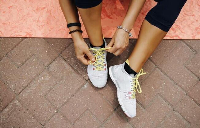 a woman tying her shoelaces on her sneakers