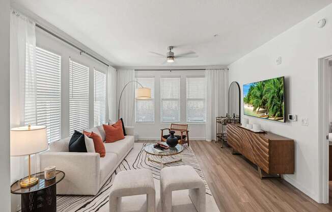 A living room with a white couch, a coffee table, and a television on the wall.