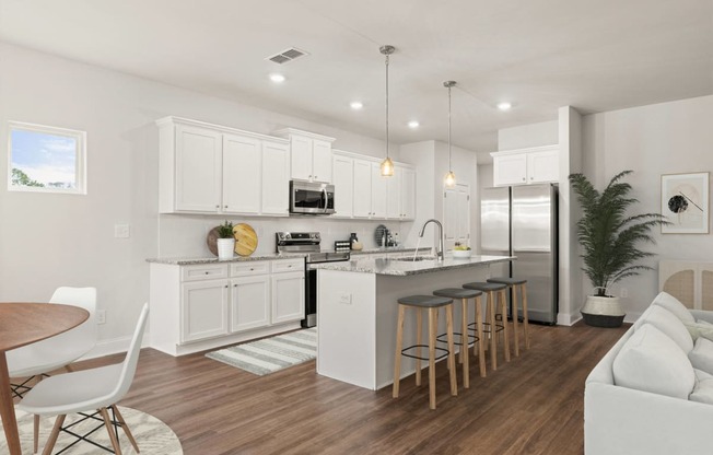 an open kitchen and living room with white cabinets and a bar with stools