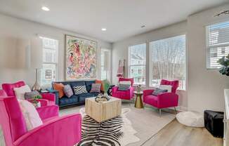 A living room with a zebra rug and a pink chair.