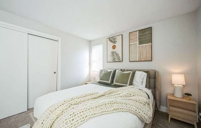 A bedroom with a bed covered in a white blanket and pillows.