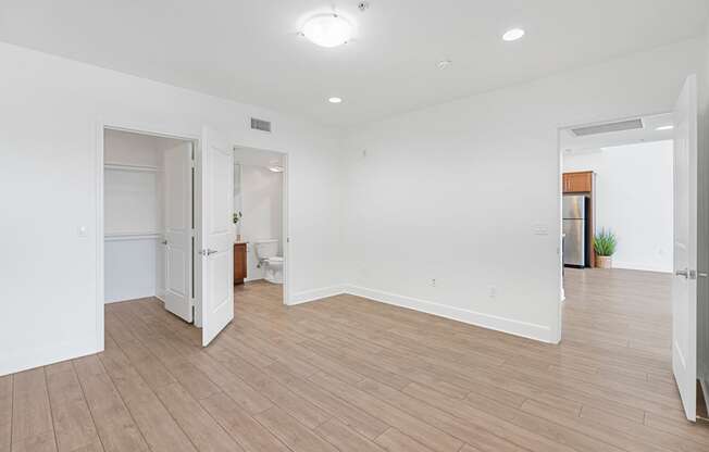 a renovated living room and kitchen with white walls and wood flooring
