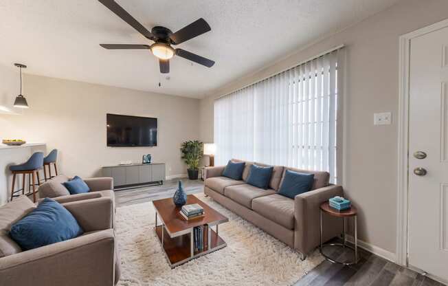 a living room with couches and a coffee table and a ceiling fan