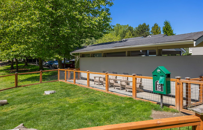 A green mailbox sits on a wooden fence in front of a house.