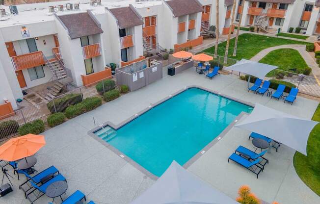 an aerial view of a swimming pool with chairs and umbrellas