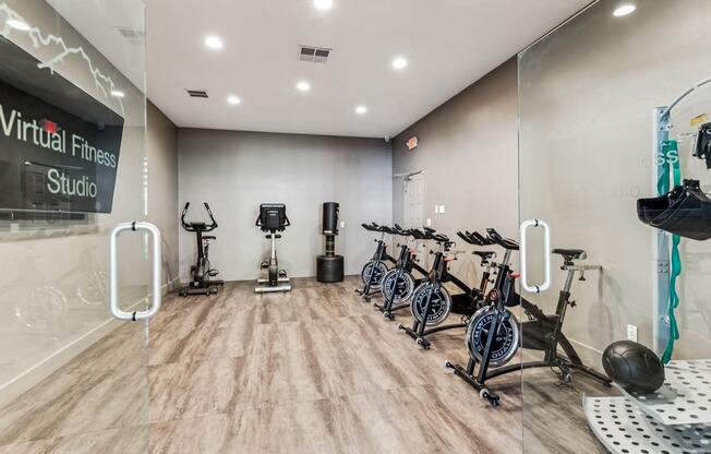 a fitness room with cardio bikes and weights on a wooden floor