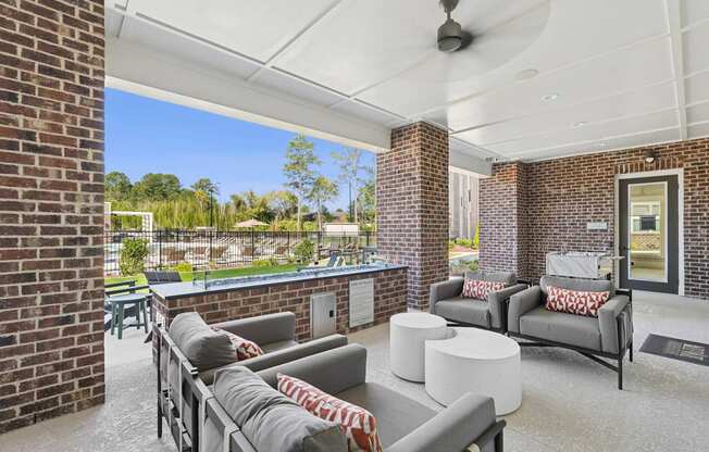 A patio with a grey couch and a white table.