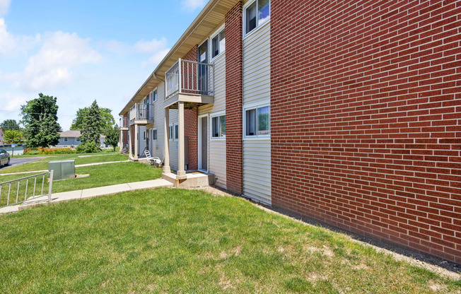 a brick apartment building with a lawn and a sidewalk