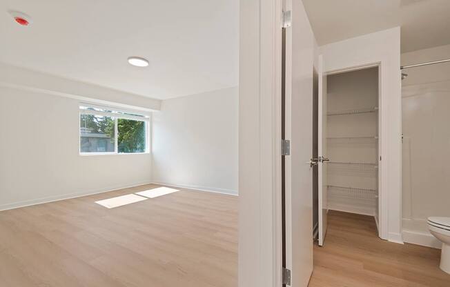 A white room with a window and a door leading to a bathroom.
