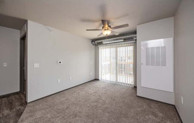 A room with a ceiling fan and a window with blinds.