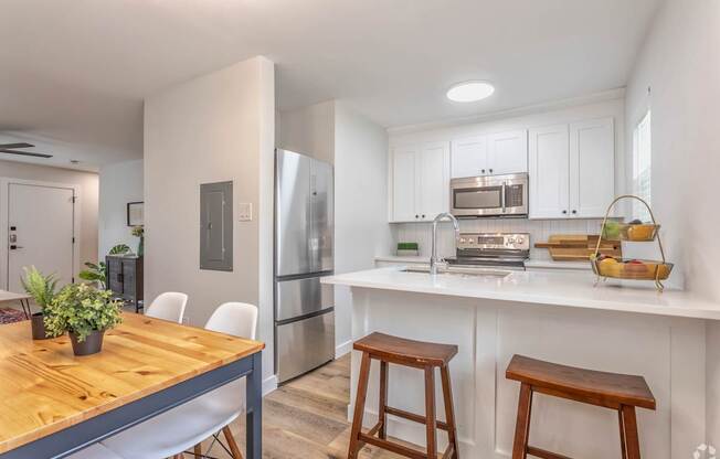 A kitchen with a wooden table and white chairs.