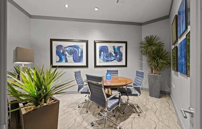 A conference room with a table, chairs, and two framed artworks on the wall.