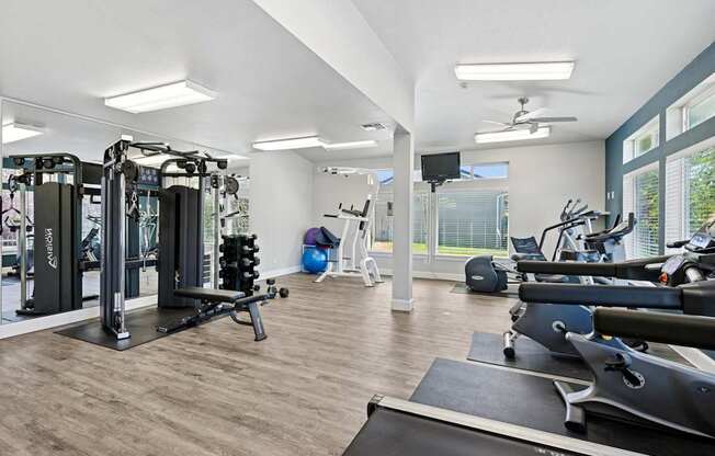 A spacious gym with a variety of equipment including treadmills, weights, and exercise machines at The Madison apartments in Olympia, WA