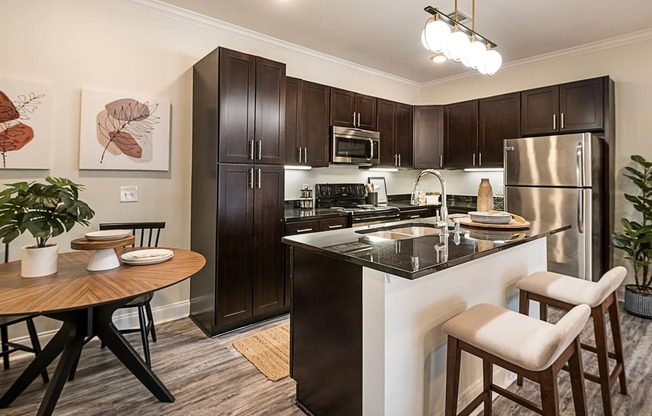 spacious kitchen with stainless steel appliances and a breakfast bar with a wooden table and chairs at Arlo Luxury homes Apartments, Little Rock, 72210