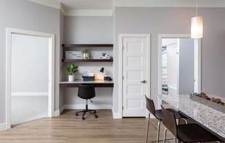A home office with a desk, chairs, and a shelf with decorative items.