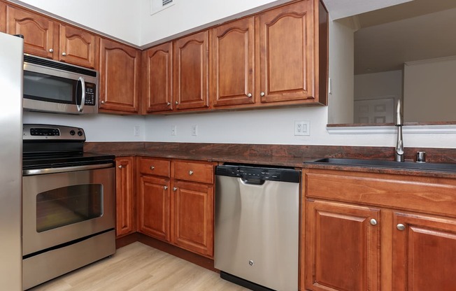 A kitchen with wooden cabinets and a black dishwasher.