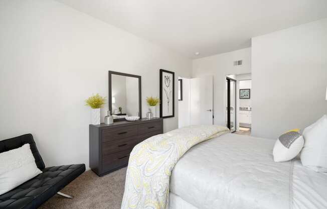 a bedroom with white walls and a large white bed with a yellow and white comforter