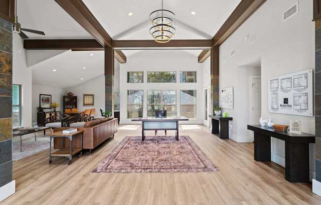 A large, open living room with a rug on the floor and a long table with chairs.