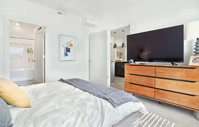 A bedroom with a bed, dresser, and a television.