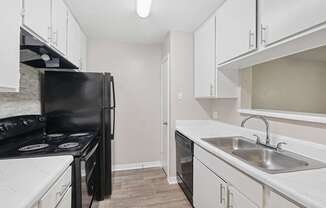 A kitchen with black appliances and white cabinets.