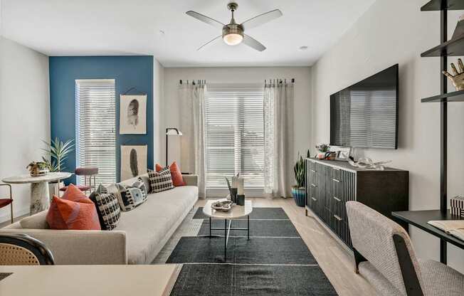 A living room with a beige couch, a coffee table, and a ceiling fan.
