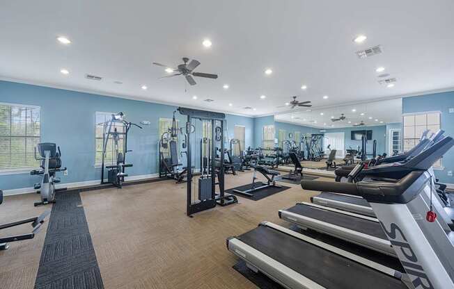 a gym with treadmills and other cardio equipment and ceiling fans
