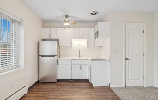 A kitchen with white cabinets and a stainless steel refrigerator.