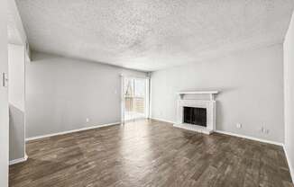 A room with a fireplace and wood flooring.