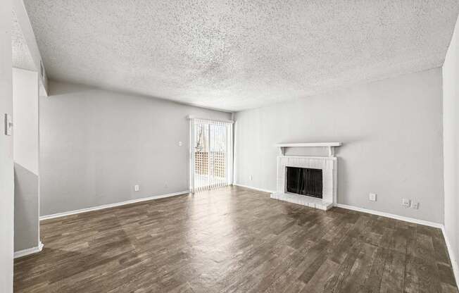 A room with a fireplace and wood flooring.