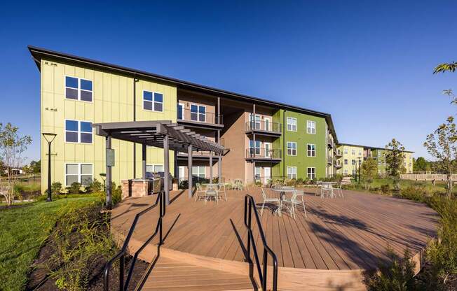 A modern building with a green and yellow exterior and a wooden deck in front.