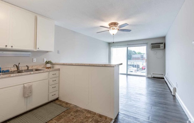 an empty kitchen and living room with a ceiling fan
