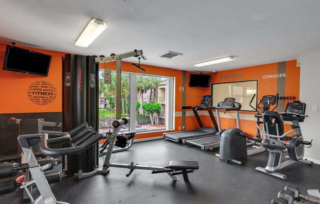 A gym with orange walls and a variety of equipment.