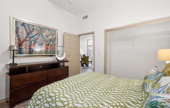 A bedroom with a bed, a dresser, and a painting on the wall.