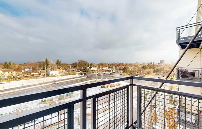 A balcony overlooks a road with cars and buildings.