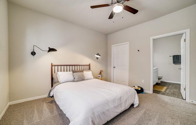 A bedroom with a bed, two lamps, and a ceiling fan.