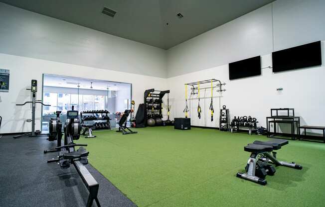 a gym with weights and other exercise equipment on a green carpet