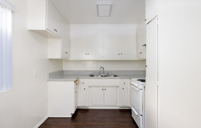 a kitchen with white cabinets and white appliances and a wood floor