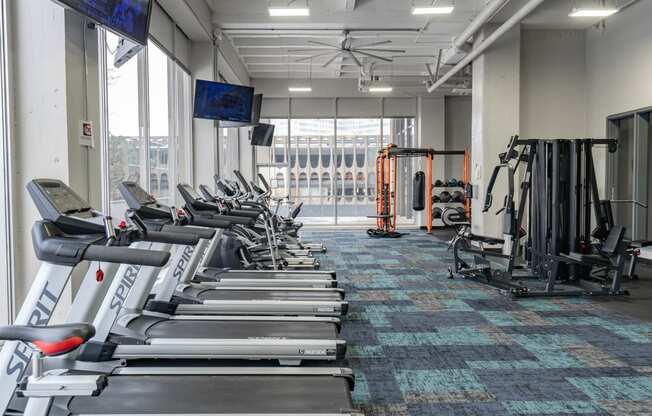 a gym with cardio equipment and a large window