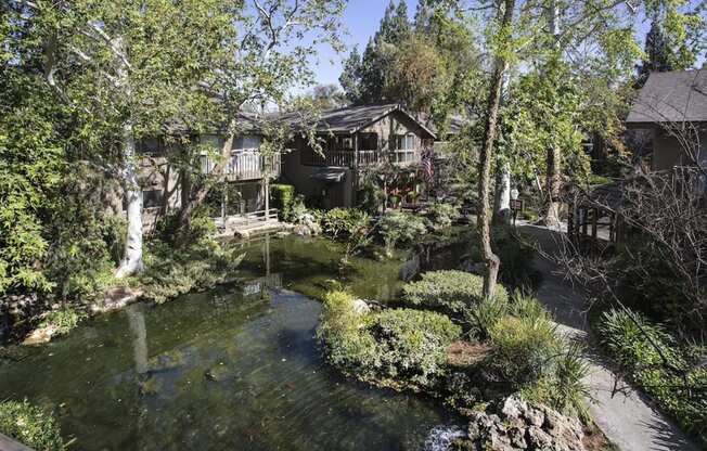 an apartment building surrounded by a pond and a house