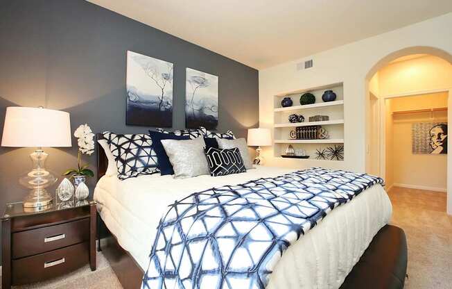A bedroom with a bed, nightstand, and wall art at The Kitt at Warner Center Apartments, Woodland Hills, CA
