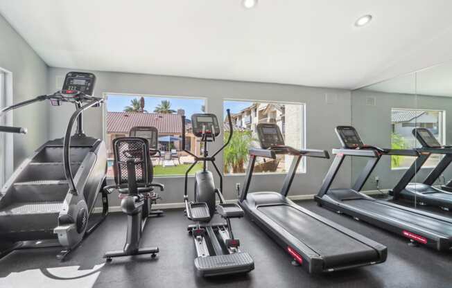 the gym is equipped with cardio equipment and a large window