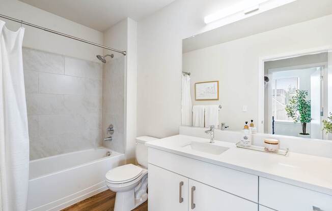 a bathroom with a white sink and toilet and a white bathtub with a shower curtain and