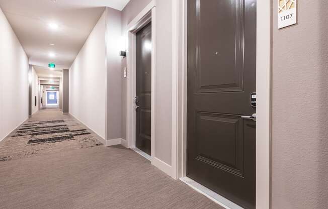 a picture of a corridor in a hotel with black doors and white walls