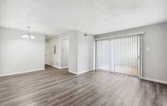 an empty living room with a sliding glass door to a balcony